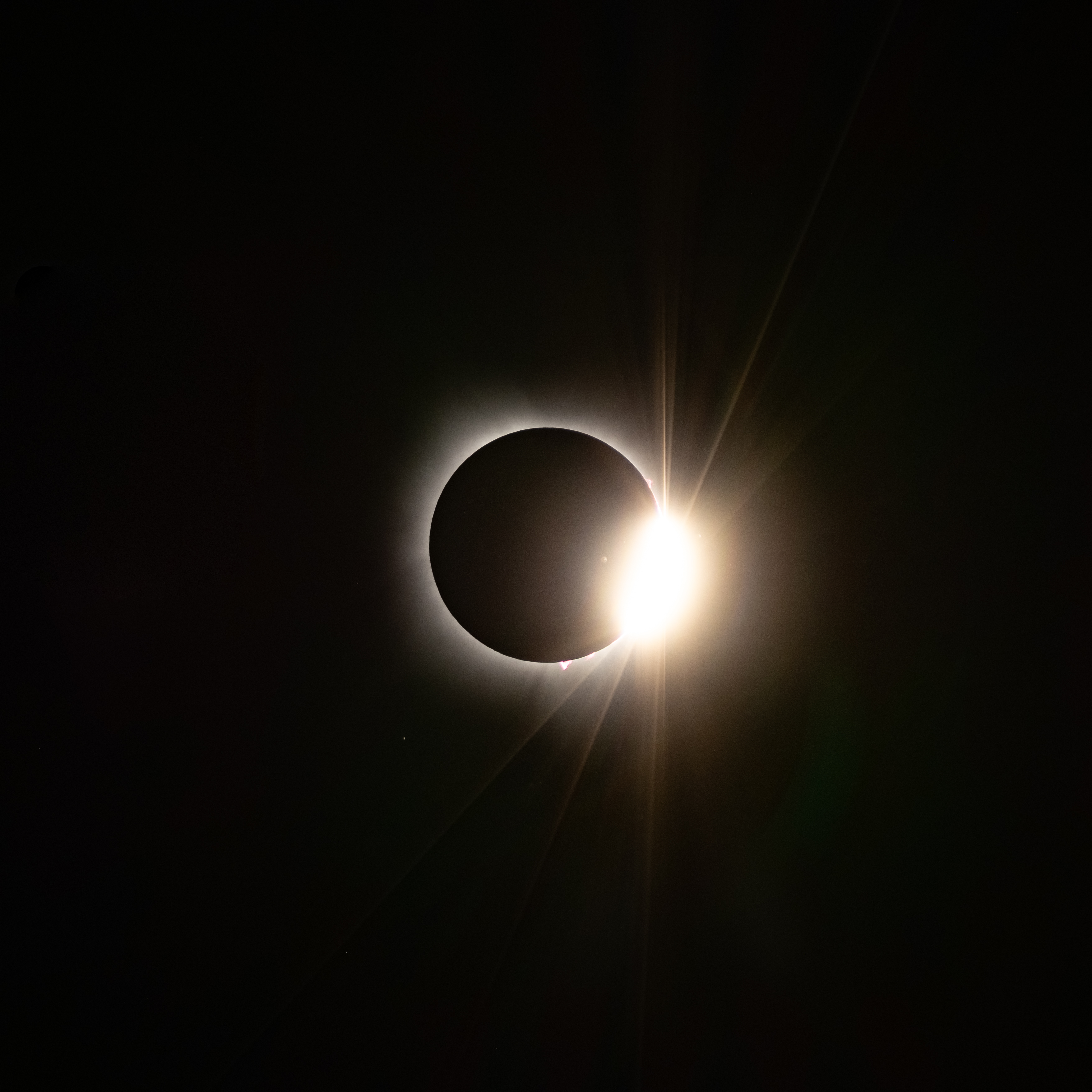 Partial eclipse with solar prominences visible at bottom and right